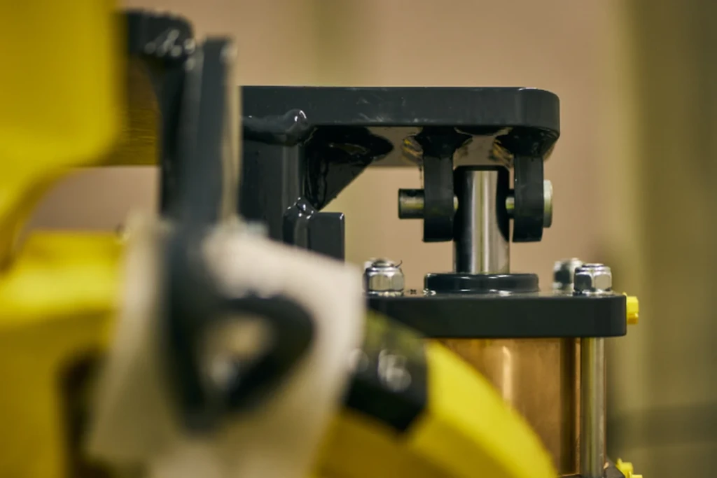 Lähikuva raidekaluston huoltokomponentista, jossa keltamustat turvamerkinnät ja kiinnitysmekanismi